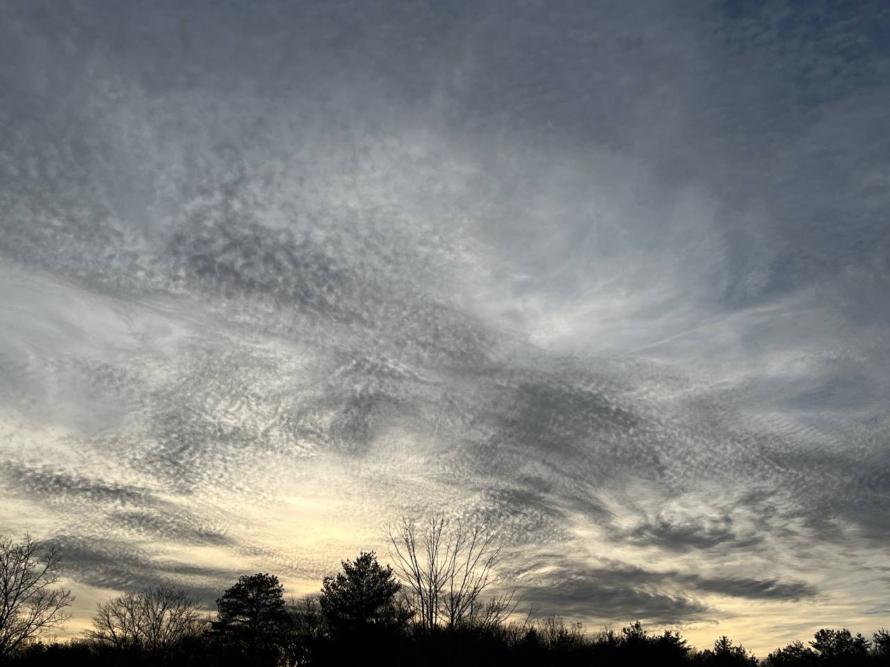 a grey swirl of clouds on the yellowing sky of a sunset